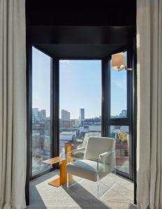 a living room with a chair and a large window at One Hundred Shoreditch in London