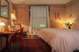 a bedroom with a bed and a desk and a table at BOHOTEL in Macclesfield