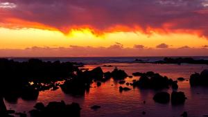 zachód słońca nad oceanem z kamieniami w wodzie w obiekcie West Coast Shores w mieście Jacobs Bay