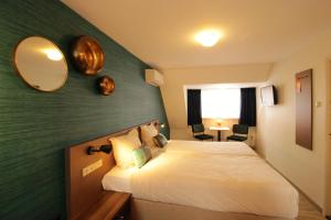 um quarto de hotel com uma cama e um espelho em Zeevonk Studio's & Appartementen em Katwijk aan Zee