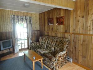 a living room with a couch and a tv at Old Towne Inne Chuckwagon Bar & Grill in Boston Bar