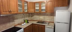 a kitchen with wooden cabinets and a white refrigerator at Neviasta Apartment in Smolyan