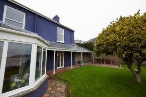 una casa azul con césped delante en The Cottage Laugharne, en Laugharne