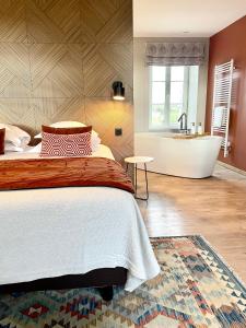 a bedroom with a bed and a bath tub at La Maison Gervaiserie & Spa in Réville