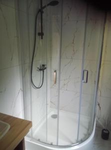 a shower with a glass door in a bathroom at Domek Jana in Mrągowo