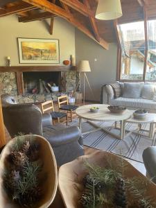 una sala de estar con sofás y una chimenea de piedra. en Hostería Las Nieves en Villa La Angostura