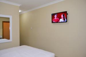 Un dormitorio con una cama y un televisor en la pared. en PALACE LODGE PINETOWN, en Pinetown