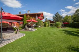 un patio verde con sombrillas rojas frente a una casa en Das Landhaus en Pfronten