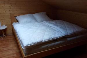 1 cama con sábanas blancas y almohadas en una habitación en Mezonetový apartmán v Osčadnici, en Oščadnica
