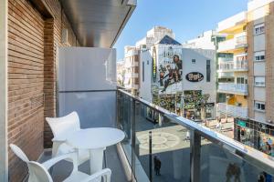 a balcony with a white table and chairs and a city at Hotel Avenida in Benidorm