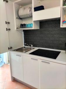 eine Küche mit weißen Schränken und einem Waschbecken in der Unterkunft I 23 PASSI GAETA in Gaeta