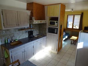 a kitchen with white cabinets and a sink and a refrigerator at Profiter du calme de la montagne vosgienne in Saulxures-sur-Moselotte