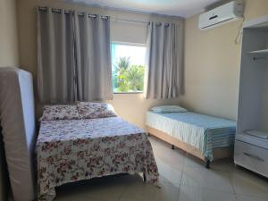 1 dormitorio con 2 camas y ventana en Casa 4 quartos no Condomínio parque de Jacuipe com acesso a praia e ao rio jacuipe, en Camaçari