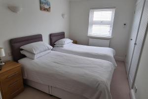 a bedroom with two beds with white sheets and a window at Beautiful 2-bed Apartment on Torquay seafront in Torquay