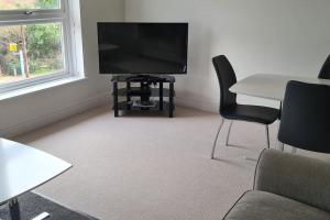 a living room with a television and a table and chairs at Beautiful 2-bed Apartment on Torquay seafront in Torquay