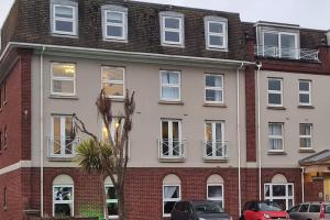 an apartment building with windows and cars parked in front of it at Beautiful 2-bed Apartment on Torquay seafront in Torquay