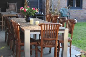 a wooden table with chairs and a vase of flowers at Het Achterhuis in Siebengewald