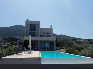 a house with a swimming pool in front of a house at Panoramic View Summerhouse in Loukísia