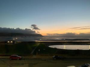 a sunset with two cars parked next to a body of water at PLAS GORWELION exclusively for adults in Llandudno