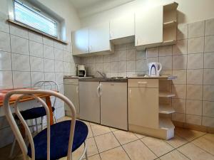 a small kitchen with white cabinets and a blue chair at Éva Panzió in Sárvár