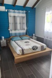 ein Schlafzimmer mit einem großen Bett mit blauen Wänden in der Unterkunft Magnifique maison en bois avec piscine in Sainte-Anne