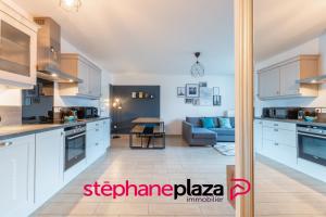 a kitchen with white cabinets and a living room at Plaza Scandinave 04 in Serris
