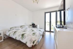 een witte slaapkamer met een bed en een groot raam bij Contemporary Villa Swimming Pool & Jacuzzi in La Roquette-sur-Siagne