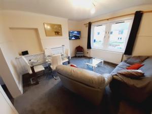 a living room with a couch and a desk and a window at Carvetii - Vincent House - Large 3 bedroom apartment with on-site parking in Fife