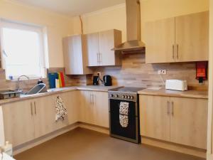 a kitchen with wooden cabinets and a stove top oven at Carvetii - Vincent House - Large 3 bedroom apartment with on-site parking in Fife