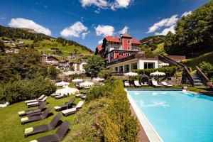 a resort with a swimming pool and chairs and a building at Boutique & Fashion Hotel Maciaconi - Gardenahotels in Santa Cristina in Val Gardena