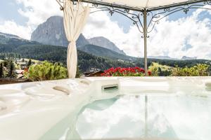 a bath tub with a view of mountains at Romantik & Family Hotel Gardenia***S in Selva di Val Gardena