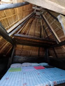 - un lit dans une chambre au toit de chaume dans l'établissement Hiwang Native House Inn & Viewdeck, à Banaue