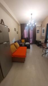 a living room with an orange couch and a table at Уютная и светлая квартира с видом на горы in Tbilisi City
