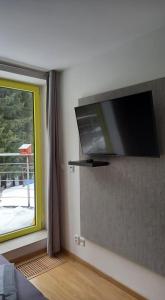 a flat screen tv on a wall next to a window at Harrachovský apartmán in Harrachov