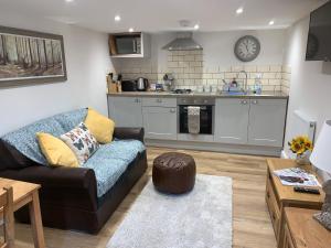 ein Wohnzimmer mit einem Sofa und einer Küche in der Unterkunft The Stables at Pentregaer Ucha, tennis court & lake in Oswestry
