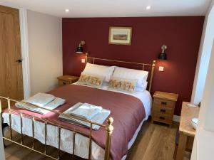 a bedroom with a bed with a red wall at The Stables at Pentregaer Ucha, tennis court & lake in Oswestry
