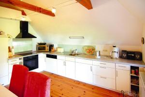 a kitchen with white cabinets and a red chair at Apartment Dycke House, Zudar in Zudar