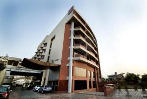 a building with cars parked in a parking lot at Clarion Bella Casa at Airport in Jaipur