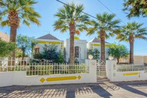 a white fence in front of a house with palm trees at Villa Albuar in Patroves