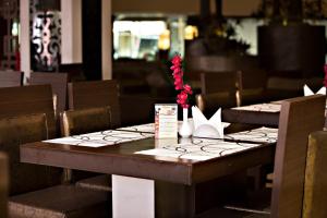 un tavolo in legno in un ristorante con sedie e un tavolo con fiori di Clarion Bella Casa at Airport a Jaipur
