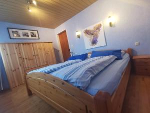 Schlafzimmer mit einem Holzbett mit blauer Bettwäsche in der Unterkunft Ferienwohnung Ammerland-Blüte in Westerstede