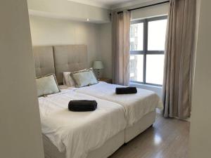 1 dormitorio con 1 cama grande y 2 almohadas negras. en Paragon Domain Light and Airy Stylishly Decorated, en Ciudad del Cabo