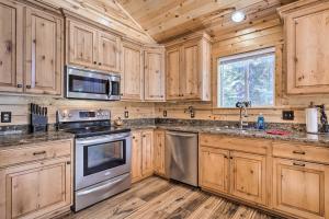 a kitchen with wooden cabinets and stainless steel appliances at Duck Creek Village Cabin with Fire Pit and Grill! in Duck Creek Village