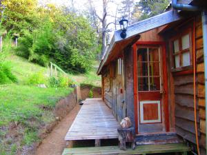 un perro sentado en una rampa de madera junto a una cabaña en Refugio Montaña Kultrun Mawida, Habitación con baño y cocina privada, en Curacautín