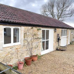 a stone cottage with white windows and potted plants at Whitley Coach House in Whitley