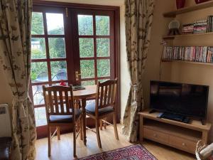 a living room with a table and chairs and a large window at Belmont Cottage in Dumfries