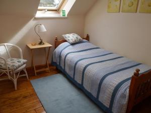 a bedroom with a bed and a chair and a window at Belmont Cottage in Dumfries