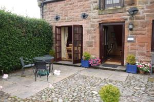 a patio with a table and chairs in front of a building at Belmont Cottage in Dumfries