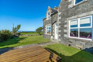 a stone house with a wooden deck in the yard at Dourie Farmhouse in Port William