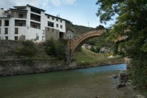 un puente sobre un río junto a un edificio en casa sobre rio Noguera Pallaresa, en Gerri